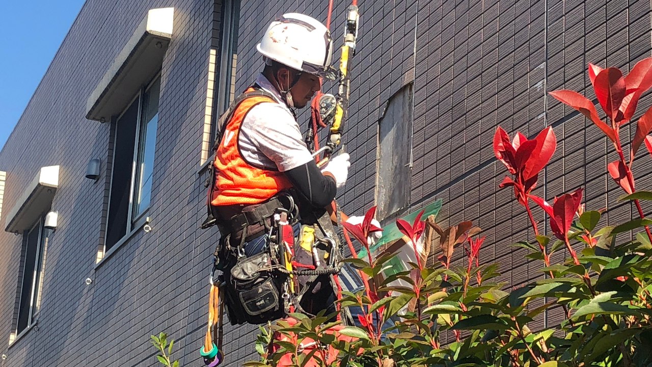 ロープで外壁の作業をする職人